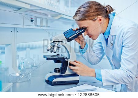 Female scientist looking through a microscope in laboratory