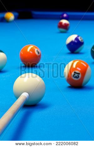 Billiard pool eightball taking the shot on billiard table with blue cloth, selective focus on white ball