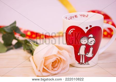 Concept of St.Valentine's Day, Love, Anniversary, Wedding with a white porcelian mug decorated with a heart image and I Love You inscription on a wooden table