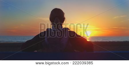 Girl sitting on a beach and looking on sinset