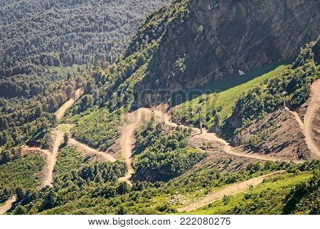 Mountain landscape: steep mountains, covered with forests, form a deep gorge, on the slope of a mountain winding road with steep turns - a mountain serpentine.