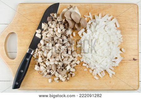 Oyster mushrooms and onions cut into cubes on a cutting board. Raw ingredients before cooking