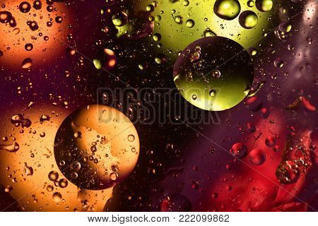 Colorful and bright background with circle oil drops that reflect yellow, orange, purple, green and red color. Color spots intentionally unfocused. Cosmic space concept.