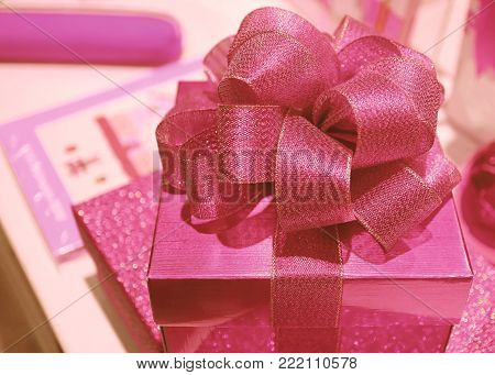 Closed up Shiny Pink Square Shaped Gift Box with Gritter Pink Ribbon Bow, Selective Focus and Blurred Background