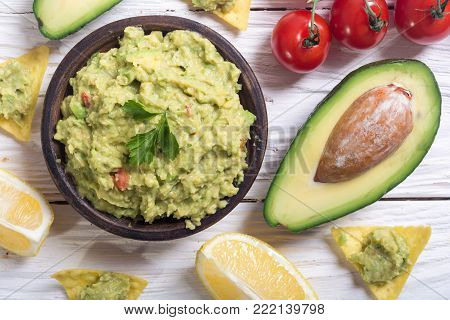 Guacamole with ingredients : avocado , lemon and tomatoes . Mexican food