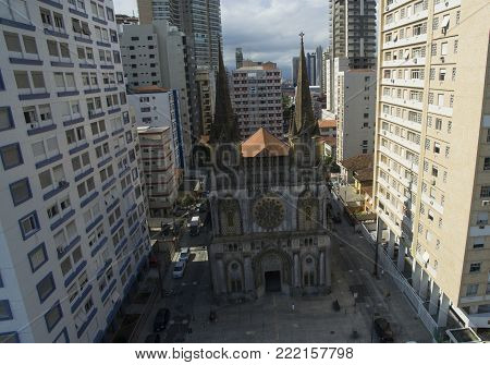 Ancient catholic church surrounded by big building in big city