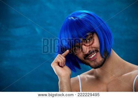 Closeup portrait of cute young male cross dressing person wearing blue wig and glasses. Place for text