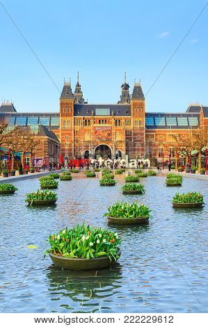 Amsterdam, Netherlands - March 31, 2016: Water and flowers, Rijksmuseum and people in front of writing, I amsterdam, Museumplein, Holland