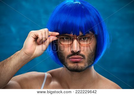 Closeup portrait of Sensual young male cross dressing person wearing blue wig and female cloth.