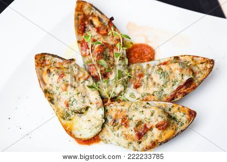 Baked mussels with parmigiano cheese and white wine in tomato coolie