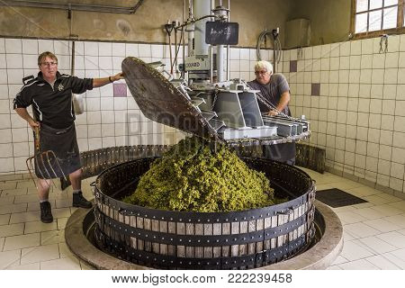 Hautvillers, France - August 11, 2017. Pressing the grapes with an old press with two working men in the Pressoir in Champagne village Hautvillers near Reims and Epernay.
