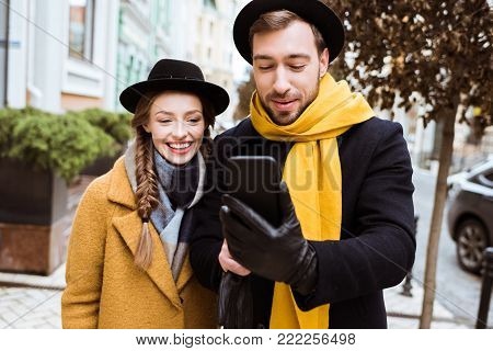beautiful young couple in autumn outfit looking at smartphone