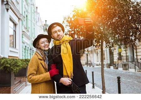 beautiful young couple taking selfie in autumn outfit