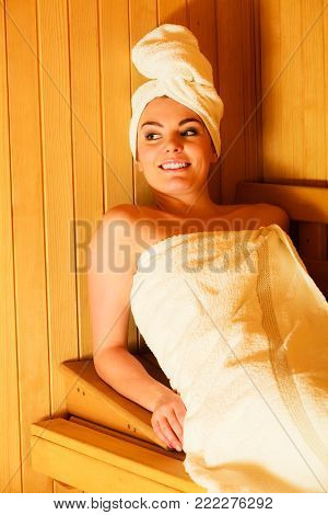 Spa beauty well being and relax concept. Woman in white towel sitting relaxed in wooden sauna