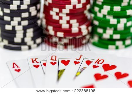 A royal flush with blurred poker chips in the background on a white background