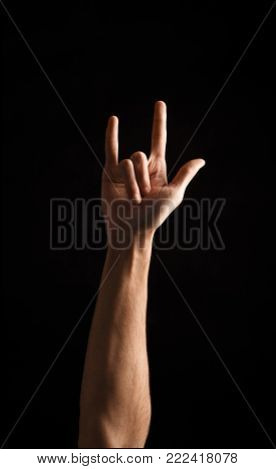 Male hand showing rock gesture or i love u sign in hand language on black isolated background. Cutout, copy space, low key