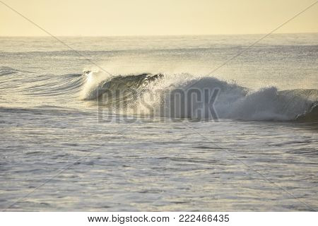 Stunning sunrise off the coast with crashing waves