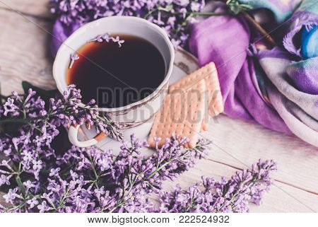 Morning Cup Of Tee, Cookies, And Lilac Flower On Wooden Table From Above. Beautiful Breakfast. Flat