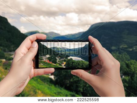 Picture of villagei in Norway on mobile phone. Female take picture houses and port in Lysefjorden on smart phone