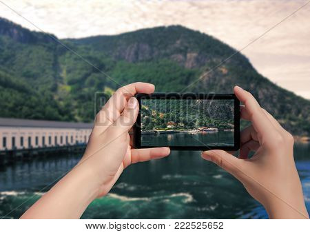 Picture of village Florli in Norway on mobile phone. Female take picture houses and port in Lysefjorden on smart phone.