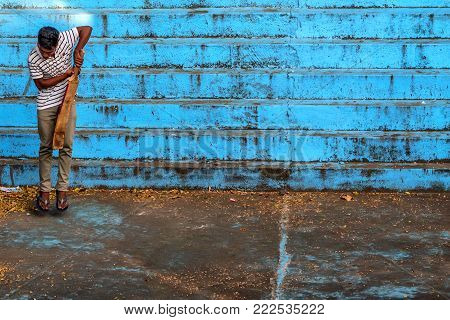 BENTOTA, SRI LANKA - CIRCA DECEMBER 2016: Local Sri Lankan man plays cricket outdoors. Cricket is a popular game in Sri Lanka.