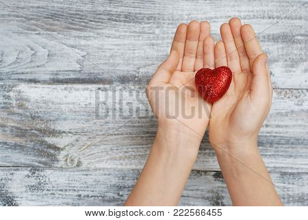 Girl Hands Holding a Sparkling Red Heart. Top View. Valentine's Day.