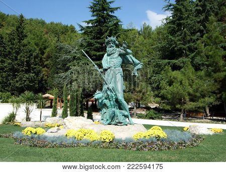 Partenit, Crimea, Russia - JULY 15, 2012: Statue Neptune holds a trident and a girl is a seashell in Aivazovsky park. Partenit park. Suuny day. Crimea. Russia