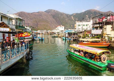 HONG KONG - APR 11, 2011: A sightseeing tour boat carrying visitors cruises along Tai O River where traditional houses built on stilts above the tidal flats of Lantau Island are homes to the Tanka people in this old fishing village of Hong Kong.