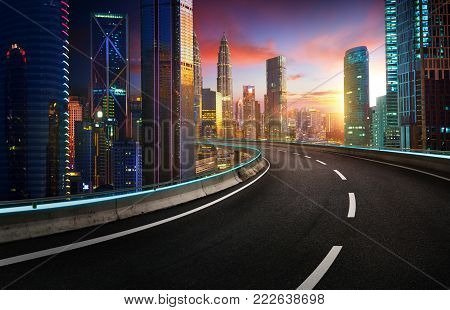 Highway overpass with modern city skyline and  skyscrapers at sunset.