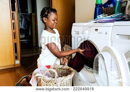 Young teen girl washing clothes using washing machine