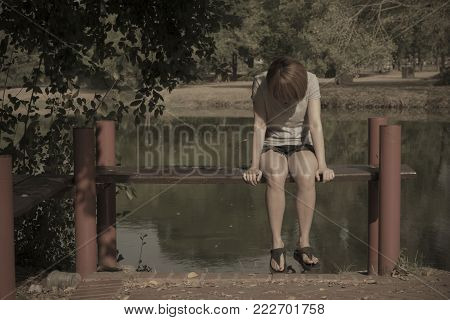 The girl sitting alone sad by the pool , in a lonely atmosphere.