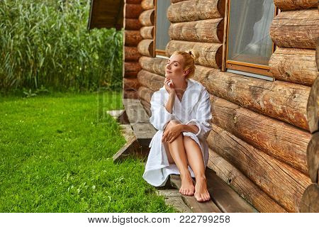 beautiful young woman in bathrobe realxing outdoors after sauna. outside shot with natural light.