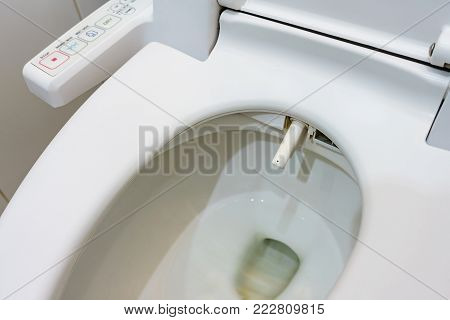 Toilet bowl with electronic control bidet. Water sprays from the toilet bowl. A cleansing jet of water designed to cleanse the anus of the user of this bidet-style toilet.