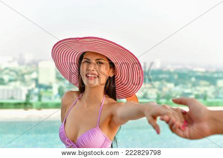 Swimsuit Concept. Beautiful girl wearing pink swimsuit. Beautiful girl in swimwear is relaxing at the swimming pool. Independent living sexy woman at the city center pool.