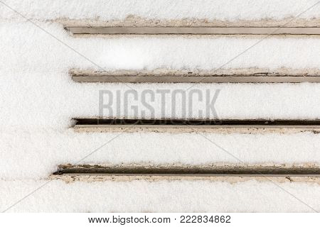 the back of a white wooden bench covered with snow