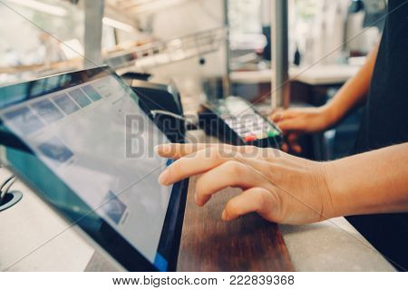 Closeup shot of caucasian cashier hands. Seller using touch pad for accepting client customer payment. Small business of coffee shop cafeteria.