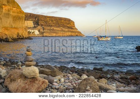 Stacked stones and boats in the water at Puerto de Mogán, Gran Canaria