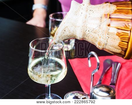 travel to France - tourist pours local white wine from jug into wineglass in outdoor cafe of Boulogne-sur-Mer city