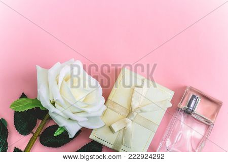 top view of rose , gift box and perfume bottle on   a pink background copy space