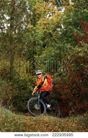 Candid Outdoor Shot Of Concentrated Young Rider In Protective Gear Sitting On His Bike