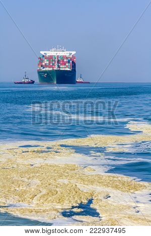 Rotterdam, the Netherlands - April 9, 2017: CSCL Pollution on the water near Venus container ship with tug boats in Rotterdam harbor