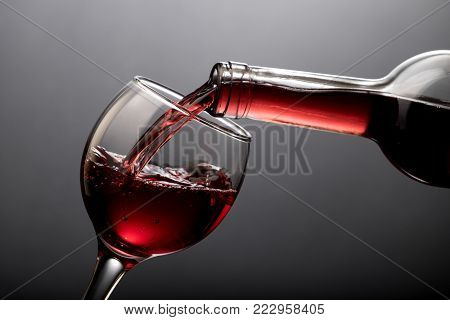 Red wine pouring into a glass isolated on black background