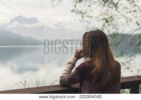 Lonely woman standing absent minded and looking at the river