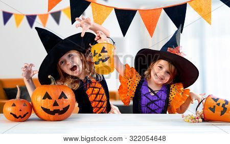 Happy Sisters With Carnival Costumes Indoors - Cheerful Children Play With Pumpkins And Candy
