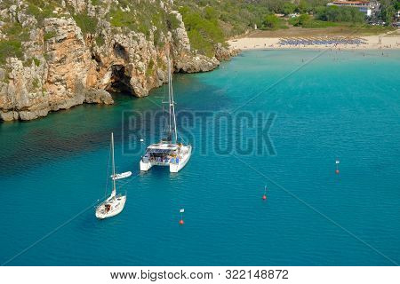 View On On The Beach Cala En Porter And White Boats On Menorca, Balearc Islans, Spain.