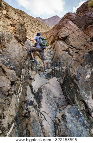 A man is hiking through a wadi in Hajar Mountains near Hatta, UAE