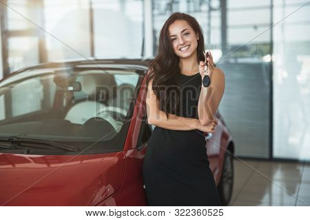 Young Beautiful Woman Looks Happy With Car Keys In Her Hand Standing In Dealership Center Buying Bra