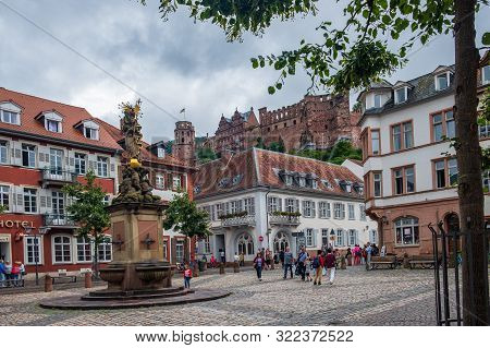 Heidelberg, Germany - August 7, 2019: The Madonna Statue In Kornmarkt Square With Heidelberg Castle 