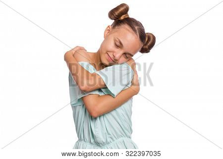 Self love and self care. Portrait of teen girl Hugging oneself, isolated on white background. Cute caucasian young teenager smiling with eyes closed. Happy funny child.