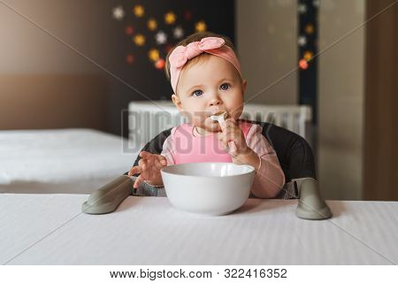 Top View. A Child Alone Stands At Home In A Crib Holding On To Her Side. Portrait Of A Nine-month-ol